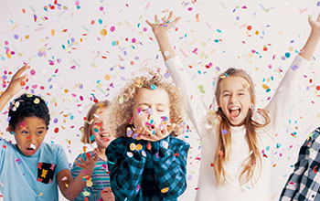 Happy group of kids having fun during birthday party with confetti