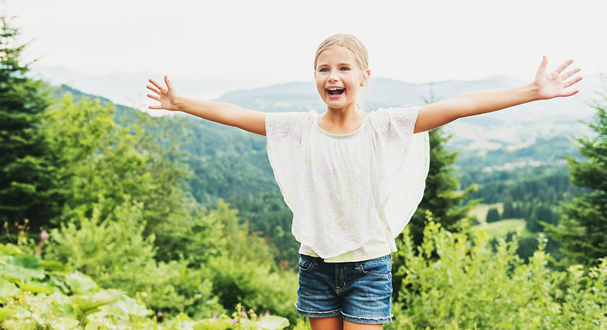 Little kid girl hiking in mountains, arms up wide open